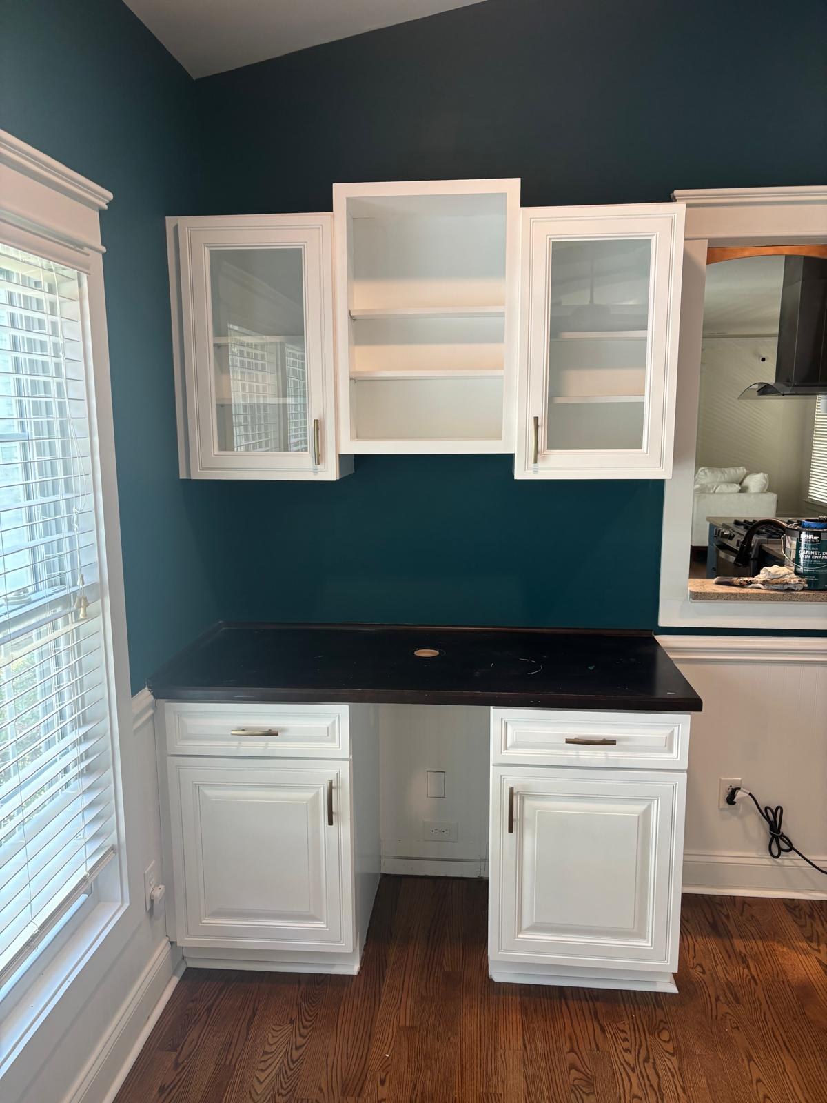 White cabinets against a deep green wall